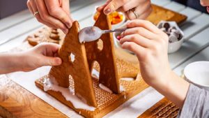 Two people building a gingerbread house as a festive christmas activity