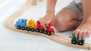 Preschooler playing with a train with each car shaped as a letter
