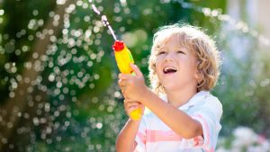 A preschooler playing with a water gun outdoors