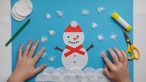 A winter craft made of cardboard with a snowman and snowballs stuck on it