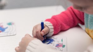 A child in a jumper drawing on a piece of paper
